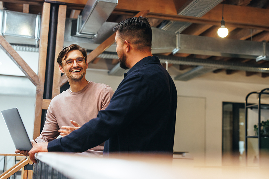 Two coworkers talking to each other about their tech work