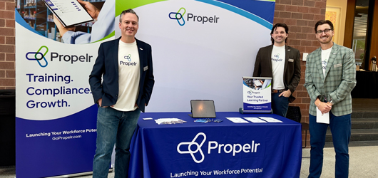 Propelr sales team in front of booth at a learning and development conference