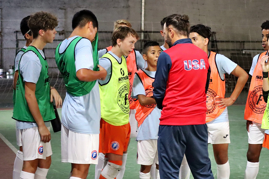 A youth soccer team being instructed by their coach